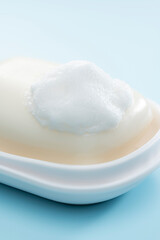 水色背景に映える泡の乗った固形石けんの清潔感あふれる日用品イメージ