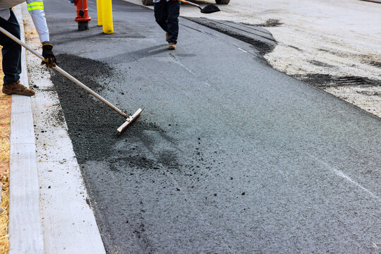 Construction workers are smoothing asphalt on anew road, focusing on quality detail