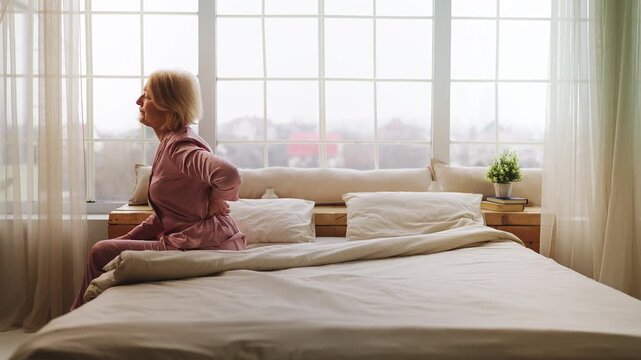 Worried senior woman suffering lower back pain, lumbar herniation and cramps