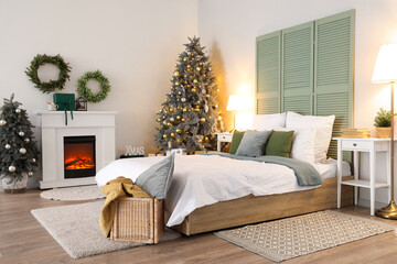 Interior of bedroom with fireplace, Christmas trees and glowing lamps