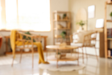 Armchairs, coffee table and shelving unit with books in interior of living room. Blurred view
