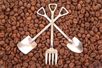 Elegant still life featuring two crossed metal shovels surrounded by roasted coffee beans, great for coffee brand promotions or rustic decor