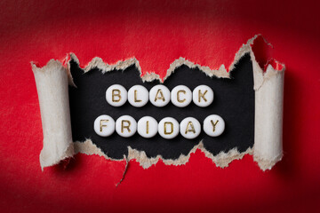 Close-up of Black Friday sale text made of acrylic beads on torn red paper. High-resolution photo.