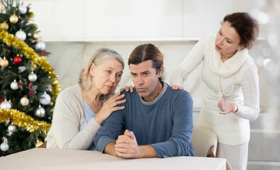 On Christmas Eve man is upset by woman claims and screaming during family quarrel, senior woman supports and calms son. Woman screams and swears at husband