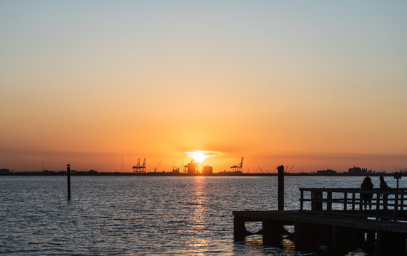 Sunset over the sea, silhouette of people on pier - Powered by Adobe