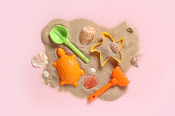 Beach toys and sand on pink background
