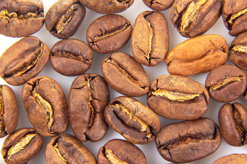 Obraz premium Up-close perspective of roasted coffee beans with visible splits and a smooth, dark brown finish on a white background. Perfect for coffee shop marketing.
