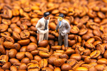 miniature figures of people among roasted coffee beans. coffee business concept