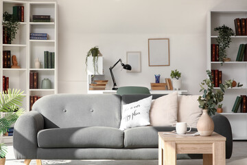 Interior of light living room with grey sofa, tables and bookshelves © Pixel-Shot