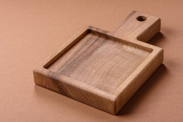 Wood, a wooden empty cutting board on a dark kitchen table. Wooden cutting board