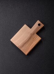 Wood, a wooden empty cutting board on a dark kitchen table. Wooden cutting board