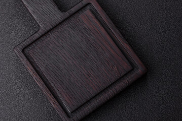 Wood, a wooden empty cutting board on a dark kitchen table. Wooden cutting board