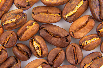 Vibrant macro image of roasted coffee beans, revealing their intricate textures and deep brown colors on a white backdrop. Ideal for gourmet food photography.