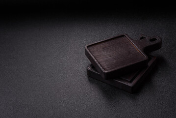 Wood, a wooden empty cutting board on a dark kitchen table. Wooden cutting board