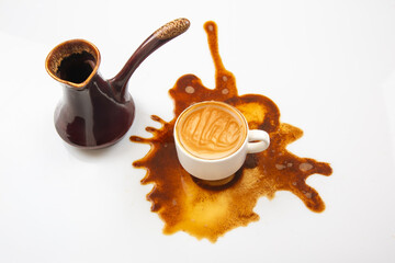 An action shot of coffee being poured from a traditional vessel into a white cup, with a striking spill splashing around, set against a clean white backdrop for a bold visual effect.