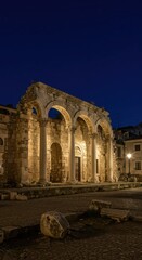 Naklejka premium Ancient stone ruins illuminated dramatically under the moonlight, creating a mysterious and historic nocturnal ambiance across the classic European city center, archway, nocturnal, serenity