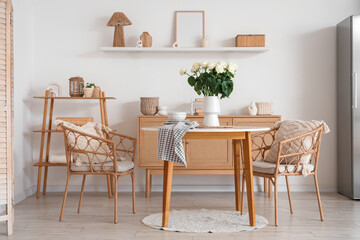 Interior of light room with white roses in vase on dining table