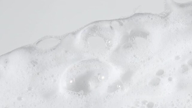 Bubbles of white soap foam. Moving Soap foam popping bubble on a white backdrop. Soap sud macro structure. Clean, cleaning concept, laundry, shower. . High quality 4k footage