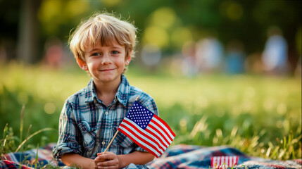 A young boy is sitting on a blanket in a grassy field holding an American flag