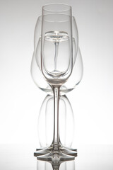 Five refined wine glasses with varied designs, their reflections shimmering on a reflective surface, ideal for wine culture or elegant interior photography.