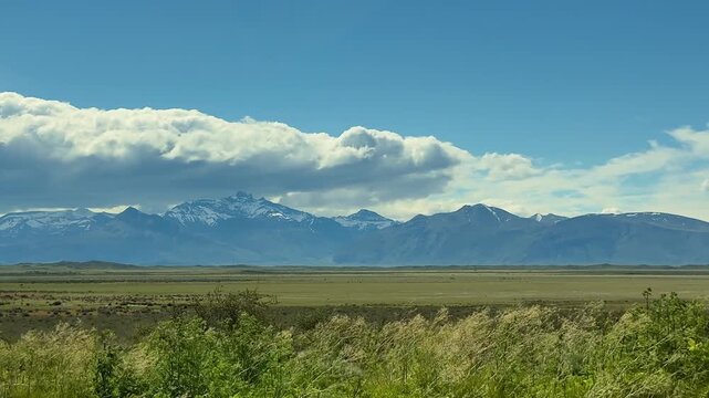 Argentina, Patagonia, viewed from a moving car window as wide plains and snowy mountain peaks pass by, showing natural scenery and the open southern landscape.
