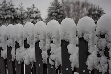 Fresh winter snow covering a wooden fence in a quiet, overcast landscape, creating a soft, natural texture and serene seasonal atmosphere