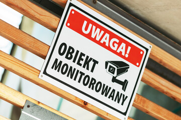 Warning CCTV surveillance sign mounted on wooden structure, security camera monitoring notice in public area, safety and protection concept
