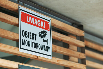 Warning CCTV surveillance sign mounted on wooden structure, security camera monitoring notice in public area, safety and protection concept