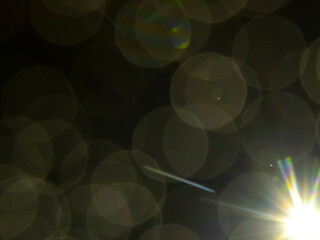 Abstract night bokeh with soft circular light patterns and a bright flare, creating a dreamy, atmospheric visual effect