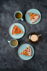 Delicious slices of sweet pastries sit elegantly on soft blue plates beside mugs of warm tea. A sense of warmth and comfort fills the afternoon scene, inviting a moment of relaxation