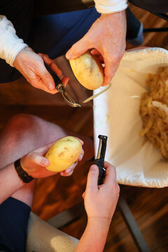 Overhead view of two men peeling potatoes for a mashed potato side dish on Thanksgiving or Christms dinner. 
