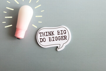 Think big, do bigger motivational quote written on note paper.