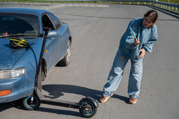 Woman examines and photographs the damage caused by a collision between an electric scooter and a car.