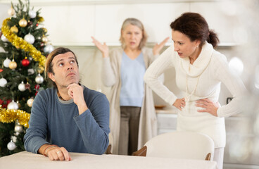 Obraz premium Elderly mother and woman during family quarrel accuse adult man during winter holiday, prove his wrong, conflict of interest