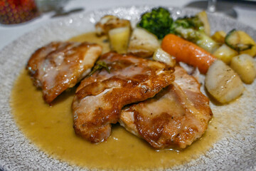 Saltimbocca alla romana made with veal, prosciutto and sage, served on a plate with sauce an vegetables, Italian style dish, selected focus