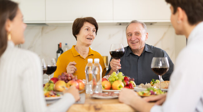 Senior man and woman sitting with their grown children during family holiday table in light kitchen