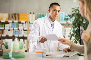 Fototapeta premium Male pharmacist advises a client on medicines and pills, he has read a medical prescription and offers pills