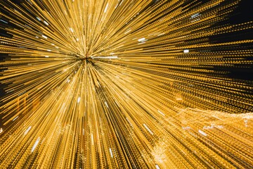 Abstract motion-blur photo of golden Christmas lights streaking outward, creating an energetic starburst effect