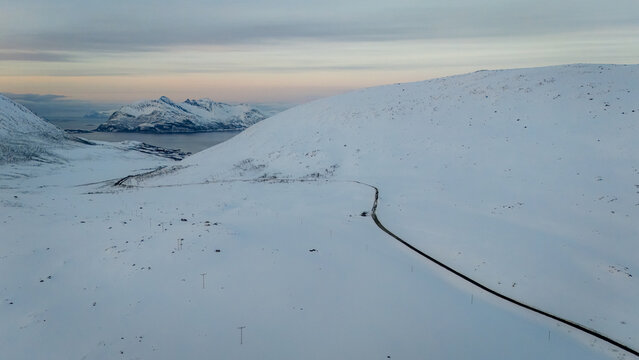 Snowy fjord road leading to Norwegian coastal village - Powered by Adobe