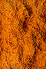 A close-up of finely ground orange spice showcases its rich texture and vivid hue. This vibrant powder suggests the essence of global cuisine, enhancing flavors and aromas
