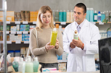 In sales area, girl examines antidandruff shampoo, chooses modern and safe product for care and consulting with man pharmacist about using cosmetic care product