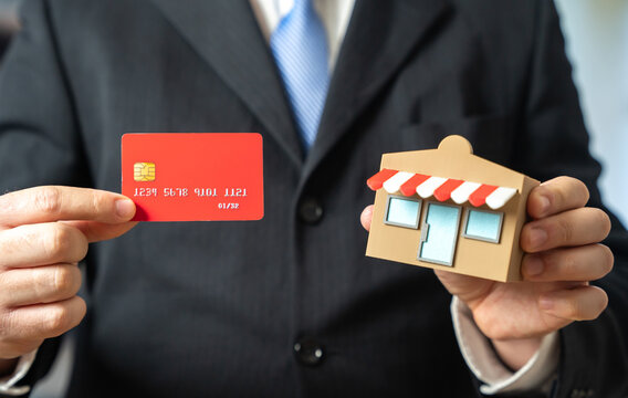 A businessman runs a store and a credit card. A bank debit card. Cashless purchases, the introduction of self-service terminals. Fintech trends, retail modernization and consumer payment behavior.