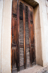 Close-up of aged dark wooden shutters with deep texture, golden central grain, and subtle metal...