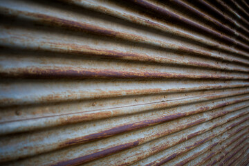 Angled close-up of corrugated metal with light gray paint and heavy rust in rich brown and orange tones. Strong industrial texture showing aging, corrosion, and weathered surface depth.