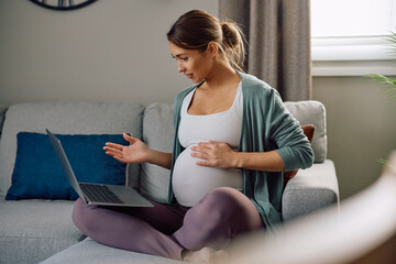 Young pregnant woman making video call over laptop at home.