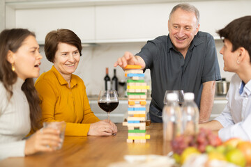 Emotional family, parents with children excitedly playing Jenga game at home