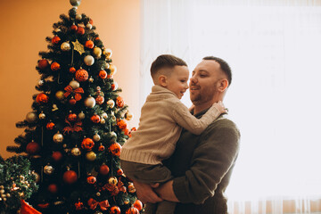 Father hugging son by decorated christmas tree