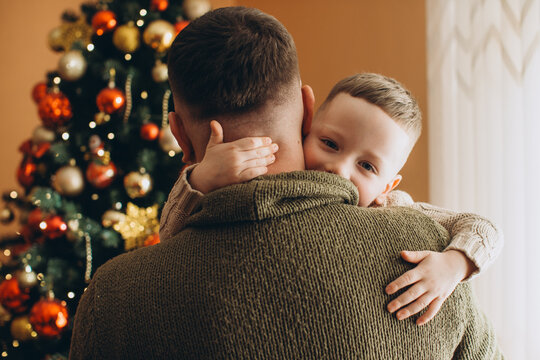 Young son hugging proud father during christmas - Powered by Adobe