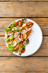 A vibrant salad features crunchy lettuce, juicy tomatoes, and crispy toppings arranged beautifully on a white plate. Natural light enhances the fresh colors, creating an appetizing scene