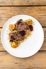 Tender roast beef is beautifully arranged on a plate, accompanied by roasted potatoes and a vibrant berry sauce. This mouthwatering dish invites everyone to enjoy a hearty meal together